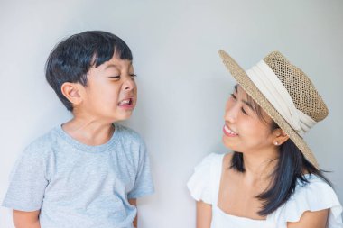 Portrait beautiful traveler asian mother in white dress, straw hat and son in grey shirt enjoys relax smile leisure at resort in tropical beach vacation.