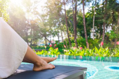 Beautiful clean woman's feet above water at swimming pool. Beautiful and elegant groomed girl's touching her foot. concept about Spa ,travel and skin care.