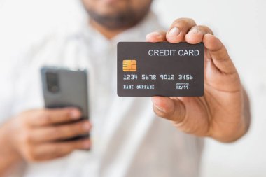 Elinde siyah kredi kartı tutan Asyalı beyaz gömlekli adamın yakın çekimi. Beyaz arka planda izole edilmiş. Finans, ticaret, iletişim, sosyal, teknoloji, ticaret kavramı.