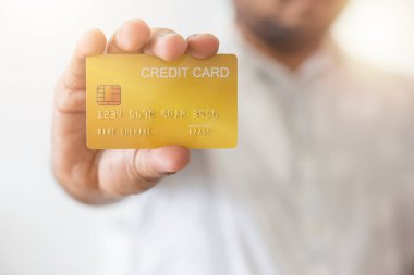 Elinde sarı altın kredi kartı tutan Asyalı adamın yakın çekimi. Beyaz arka planda izole edilmiş. Finans, ticaret, iletişim, sosyal, teknoloji, ticaret kavramı.