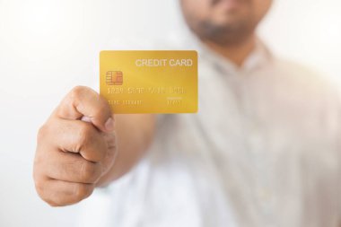 Elinde sarı altın kredi kartı tutan Asyalı adamın yakın çekimi. Beyaz arka planda izole edilmiş. Finans, ticaret, iletişim, sosyal, teknoloji, ticaret kavramı.