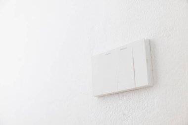 Işık anahtarı, yakın plan beyaz plastik mekanik düğme beyaz bir duvara monte edilmiş..