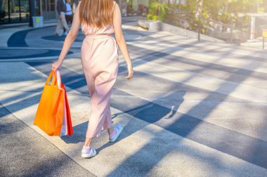 Perakende mağazasından alışveriş yaptıktan sonra elinde poşetlerle dolaşan genç bir kadın. Tüketim ve Alışveriş Konsepti Çekimi.