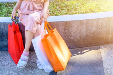 Perakende mağazasından alışveriş yaptıktan sonra elinde torba ve kredi kartı tutan genç bir kadının görüntüsü. Tüketim ve Alışveriş Konsepti Çekimi.