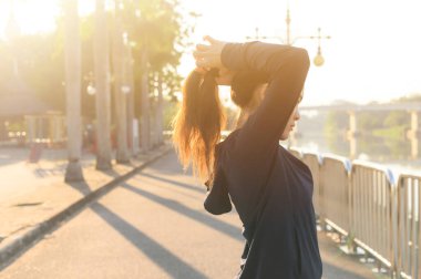 Genç Asyalı bir kadının koşmadan ya da antrenmandan önce saçını arkaya atması. Açık hava eğitiminden önce kendini hazırlayan kadın kavramı..