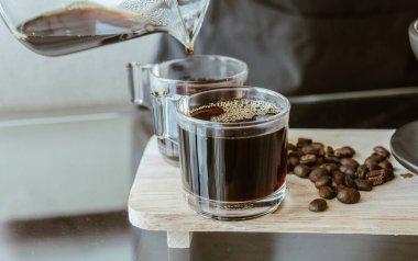 Barista 'nın bir bardak kahveye damlattıktan sonra sıcak kahve koyduğu bir kare. Kendi kendine damlatan kahve yapma kavramı..