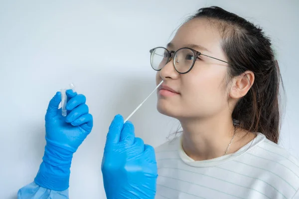在医生的密切合作下 试图从亚洲妇女身上取出鼻腔抹片 以检测对Covid 19感染的诊断 鼻咽拭子是从鼻咽中提取细胞样本的一种检测方法 — 图库照片