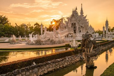 Tayland 'ın Chiang Rai ilindeki beyaz tapınağın (Wat Rong Khun) güzel manzarası gün batımında. Wat Rong Khun, Taylandlı ünlü görsel ressam Chalermchai Kositpipat tarafından tasarlandı..