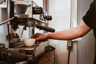 Espresso makinesini espresso kahve yapmak için kullanırken görülüyor. Espresso makinesi taze kahve hazırlayan bir araçtır..