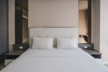 Otel odası dekorasyonunda rahat bir kraliçe yatağı manzarası. İnsanların uyuduğu bir evde konsept bir oda.