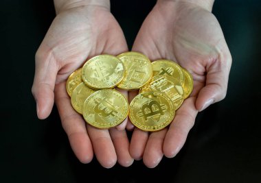 Siyah masa arkasında altın Bitcoin tutan birine yaklaş. Bitcoin popüler bir kripto para birimi, yeni bir tür para.. 