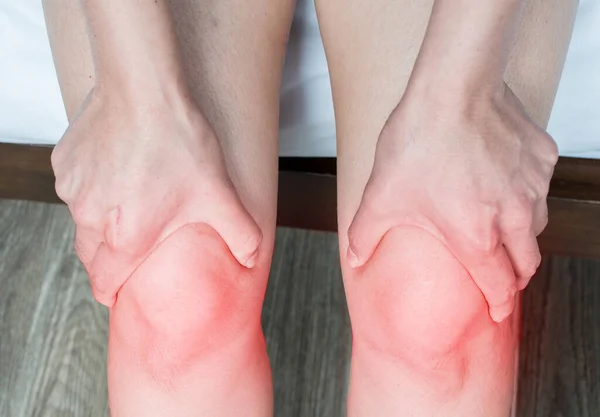 Diz ağrısı çeken ve dizine masaj yapan bir kadın eli. Diz ağrısı kopmuş bağ ya da kıkırdak yırtılması gibi bir yaralanmanın sonucu olabilir..