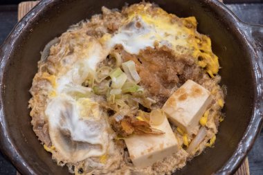 Geleneksel Japon yemekleri Karışık Toji 'ye yakın çekim. Malzemeler gevrek domuz pirzolası, yağda kızartılmış karides ve yumuşak yumurtalarla özenle pişirilmiş yılan balıkları tarafından pişiriliyor..