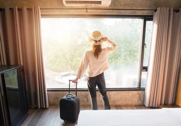 Otele giriş yaptıktan sonra genç bir yolcunun arka görüntüsü ve pencerenin dışında güzel bir manzara arıyor. Seyahat ve tatil kavramı.