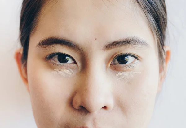 Close up shot of Asian woman face marking and applying cream concealer on her under eyes. Concealer is a type of cosmetic that is used to mask dark circles, age spots, large pores etc.