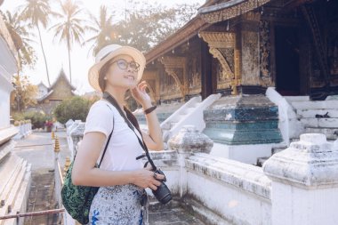 Laos 'un kuzeyindeki UNESCO dünya mirası kasabası Luang Prabang' daki ikonik tapınak Wat Xieng Thong 'u ziyaret eden Asyalı turistin portresi. Turistlerin tatil ve tatilden hoşlanması kavramı.