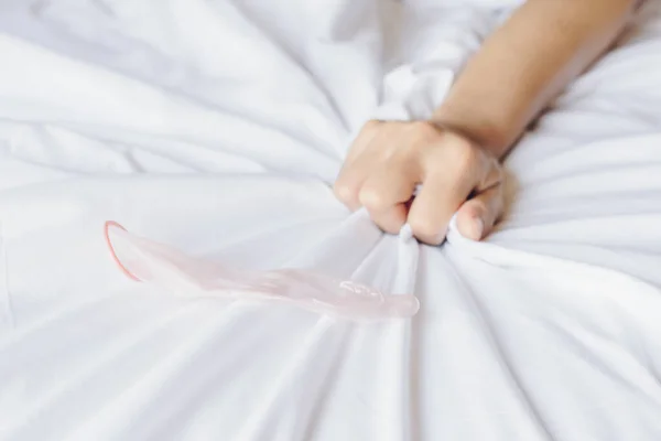 用女用手拉并抓起白色床单在床上使用安全套的截图 女用手签署性高潮 — 图库照片