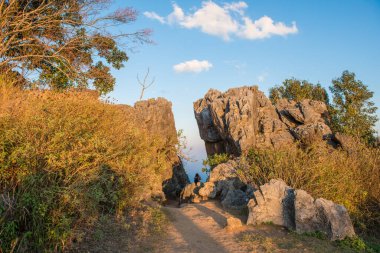 İki büyük kayanın ortasında oturan turist, Tayland 'ın Chiang Rai bölgesindeki yüksek dağlar olan Doi Pha Tang' daki Tayland-Laos sınırı arasında oldukça dramatik bir manzara izliyor..
