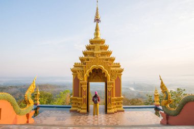 Wat Phra 'nın bakış açısında duran turist kadın Doi Phra Chan gün doğumunda Tayland' ın Lampang bölgesindeki tepelerdeki en güzel Budist tapınaklarından biridir..