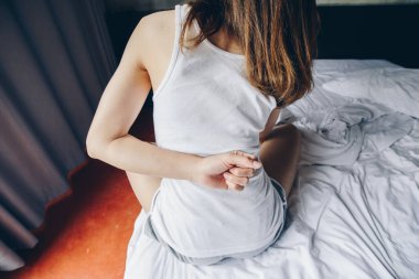 Yatak odasında uyandıktan sonra sırt ağrısı ya da bel ağrısından muzdarip genç bir kadının yakından görüntüsü. Ani sırt ağrısından acı çeken bir kadın kavramı..