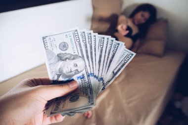 Cropped shot of man paying America dollars money to prostitute for sex. Prostitution concept.
