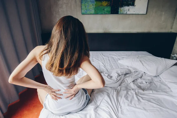 年轻女子在卧室醒来后背痛或腰酸背痛的后视镜 妇女突然背痛的概念 — 图库照片