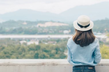 Back side of young Asian traveling woman looking to the beautiful landscape of Northern Thailand, traveller and tourist concept.