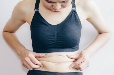 Woman touching her fat belly, woman's hand holding excessive belly fat.