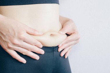 Bir kadının eli aşırı göbek yağını tutuyor. şişman şişman kadın göbeği.