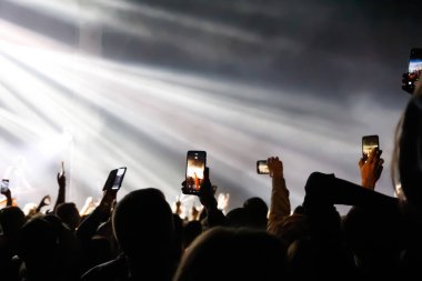 Volodymyr, Ukrayna - 21.08.2021: Rock konserinde elinde akıllı telefon bulunan birçok kişinin dikkatini dağıtır ve canlı yayın yapar. Fotoğraf çeken insanlar canlı müzik konseri sırasında telefona dokunuyor. Odaklanamıyorum.
