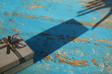 Koyu gölge yansıma gri hediye kutusu. Mavi yansıyan el, turkuaz, eski ahşap arka plan. Şimdiki kutu, yaratıcı resim. Tatil konsepti. Pis Grunge masası.