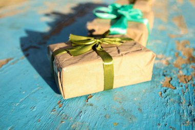 İki, iki paket, zeytin rengi ipek kurdeleli hediye kutusu mavi, turkuaz, eski ahşap arka plan. El işi kağıdında, gölgeli yeşil fiyonklu hediye kutusu. Tatil konsepti. Yakın plan. Yan görünüm.