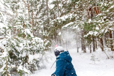Oğlan kıza bir kartopu attı. Winter Park 'ta kar topu oynayıp dışarıda vakit geçiren komik çocuklar. Kış karlı ormanlık. Kar fırtınasında soğuk soğuk hava. Ergenlik. Arka görünüm.