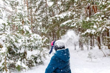 Oğlan kıza bir kartopu attı. Winter Park 'ta kar topu oynayıp dışarıda vakit geçiren komik çocuklar. Kış karlı ormanlık. Kar fırtınasında soğuk soğuk hava. Ergenlik. Arka plan.