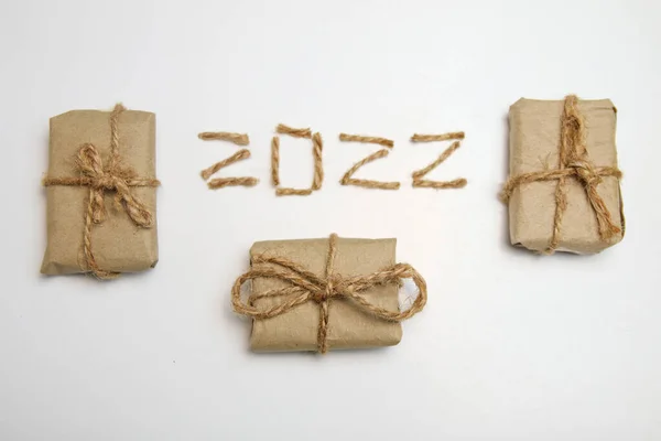 Braune Öko-Geschenkboxen. Zahl 2022. Frohes neues Jahr 2022. Neujahrskonzept, das das neue Jahr 2022 begrüßt, geschrieben von Bastelseil oder Jute auf weißem Hintergrund. Zweitausendzweiundzwanzig. Rahmen. Isoliert. Ansicht von oben — Stockfoto