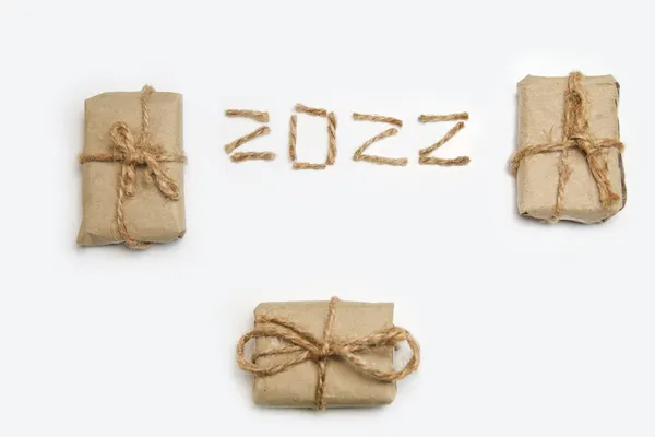 Braune Öko-Geschenkboxen. Zahl 2022. Frohes neues Jahr 2022. Neujahrskonzept, das das neue Jahr 2022 begrüßt, geschrieben von Bastelseil oder Jute auf weißem Hintergrund. Zweitausendzweiundzwanzig. Isoliert. Nahaufnahme. Beige — Stockfoto