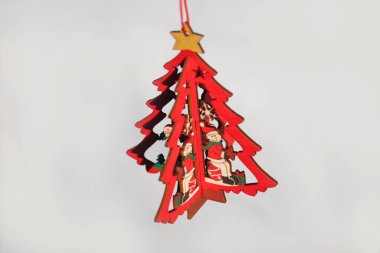 Noel ağacı oyuncağı. Beyaz arka planda izole edilmiş ahşap küçük model çam ağacı kıvrak zekalı sarı yıldız. Noel ağacı sallanıyor. Tebrik kartı. Uzayı kopyala Beyaz arka plan. Kırmızı oyuncak.