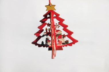 Noel ağacı oyuncağı. Beyaz arka planda izole edilmiş sarı yıldızlı küçük ahşap bir çam ağacı. Noel ağacı sallanıyor. Kutlama kartı. Boşluğu kopyala.