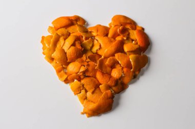 Beyaz bir zemin üzerinde portakal ve mandalina kabuklarından alınmış defocus portakal rengi kalp şeklindeki Noel arkaplanı. Bir sürü küçük kurumuş kabuk. Kış konseptine bayılırım. Kalıplı. Odaklanamıyorum.