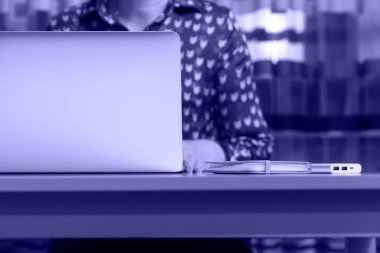 Evde bilgisayarla çalışan tanınmayan bir kadın. Bir iş günü başlar ya da biter. Çalışma masasında ve laptopta oturan genç bir kadın. İş yeri. Bir kadın. 2022 yılının rengi. Çok güzel..