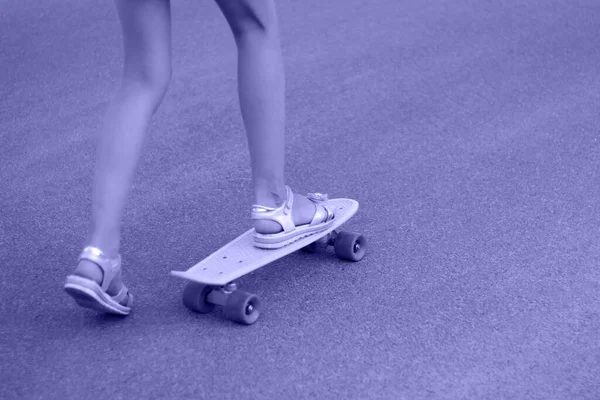 路上で黄色のスケートボードで遊んでいる熱心な女の子 白人の子供はペニーボードに乗ってスケートボードを練習している 幼少期のコンセプト 2022年の色 ペリー ティントだ 集中できない — ストック写真