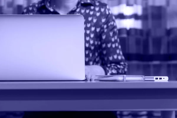 Evde bilgisayarla çalışan tanınmayan bir kadın. Bir iş günü başlar ya da biter. Çalışma masasında ve laptopta oturan genç bir kadın. İş yeri. Bir kadın. 2022 yılının rengi. Çok güzel..