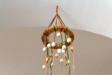 Paskalya yumurtası çelengi. Pastel arka planda bej paskalya yumurtalı ev yapımı iç dekorasyon çelengi. Yaratıcılık sanatı konsepti. Ukrayna geleneği. Tavanda avize asılı.