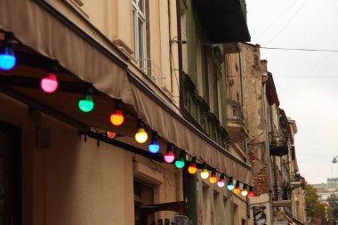 Renkli ampuller. Klasik mimari detayları. Ampullü eski bir cephe. Dekoratif dış aydınlatma. Klasik mimari. Eski binanın dış duvarları. Ukrayna, Lviv. Bulutlu yaz.