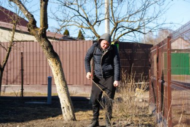 Organik ekolojik tarım. Çiftçi bozuntusu, bahar bahçesindeki böceklere elle böcek ilacı püskürtüyor. Tarım ve bahçıvanlık. Kimyasal püskürtme frenk üzümü çalısı odak dışı.