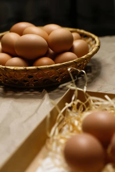 Closeup rustic eggs on black background. Easter craft box with brown eggs on eco background. Chicken eggs on craft table with hay and straw. Close-up view of raw product. Wooden straw. Eco farm.