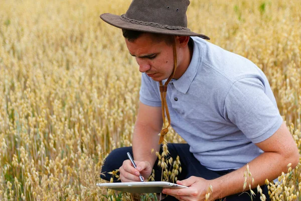 数字农场 黄金麦田农民座位的肖像和石碑上的文字 一个戴着牛仔帽的年轻人在田里察看小麦 燕麦谷物工业 — 图库照片