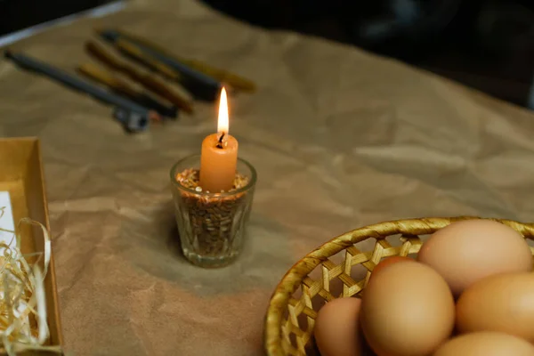 光的烛光 粗俗的背景 用于装饰帕斯卡鸡蛋的工具 皮桑卡收集鸡蛋 自制钢笔和融化的蜂蜡用来画鸡蛋 准备度假 手工艺纸 — 图库照片