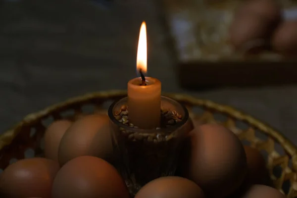 Vela com luz. Fundo rústico. Ovos Pascal, Pysankas. Coleta de ovos no fundo. Preparação para férias. Papel artesanal. Tradição. Ortodoxa. Noite escura — Fotografia de Stock