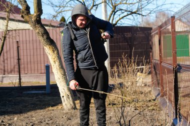 Pedikür ilaçlama, haşere kontrolü. Çiftçi bozuntusu, bahar bahçesindeki böceklere elle böcek ilacı püskürtüyor. Tarım ve bahçıvanlık. Kimyasal püskürtme çalısı. Odaklanamıyorum